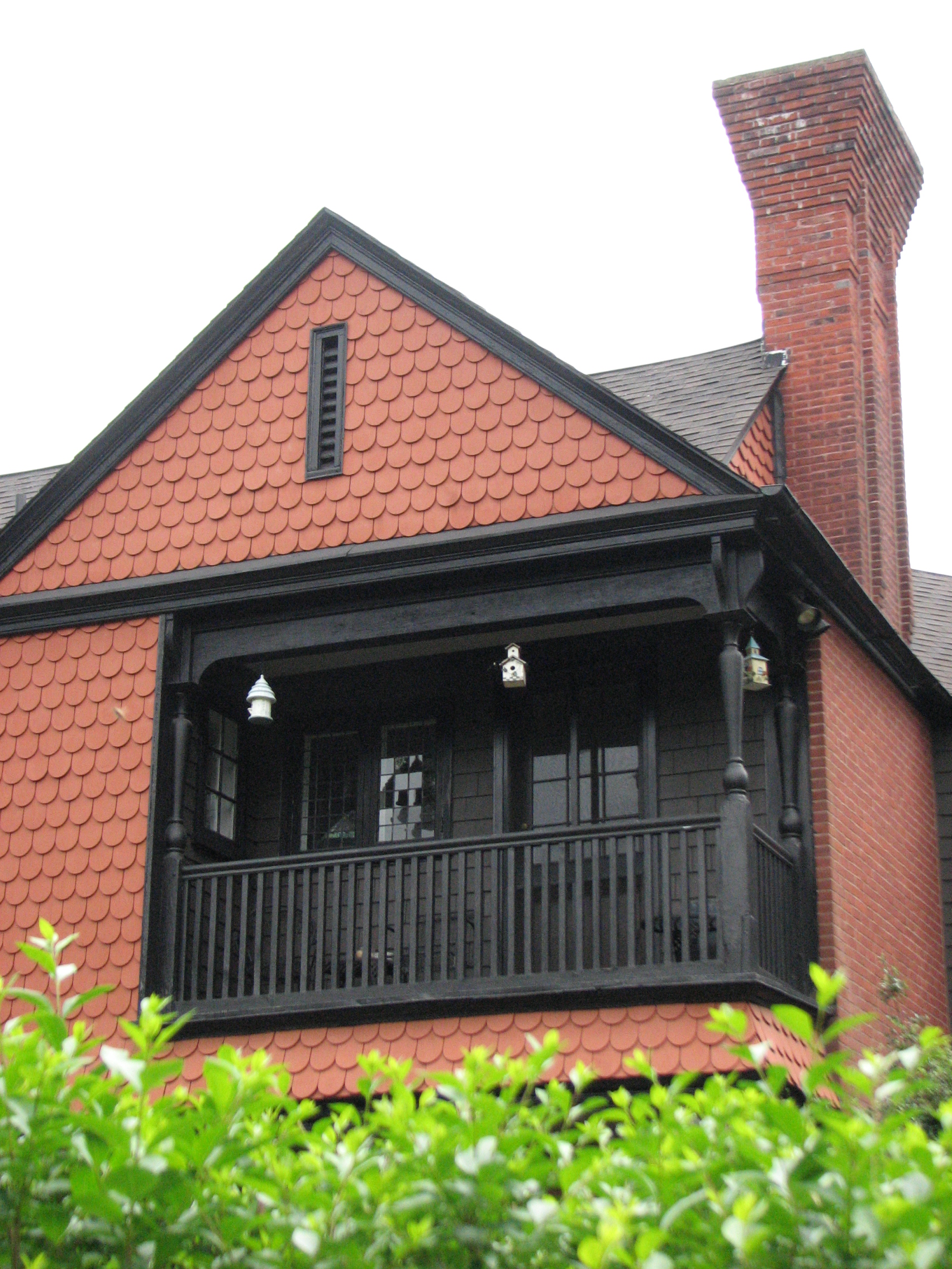 A corbelled chimney and shingle skin surround a third-floor balcony.