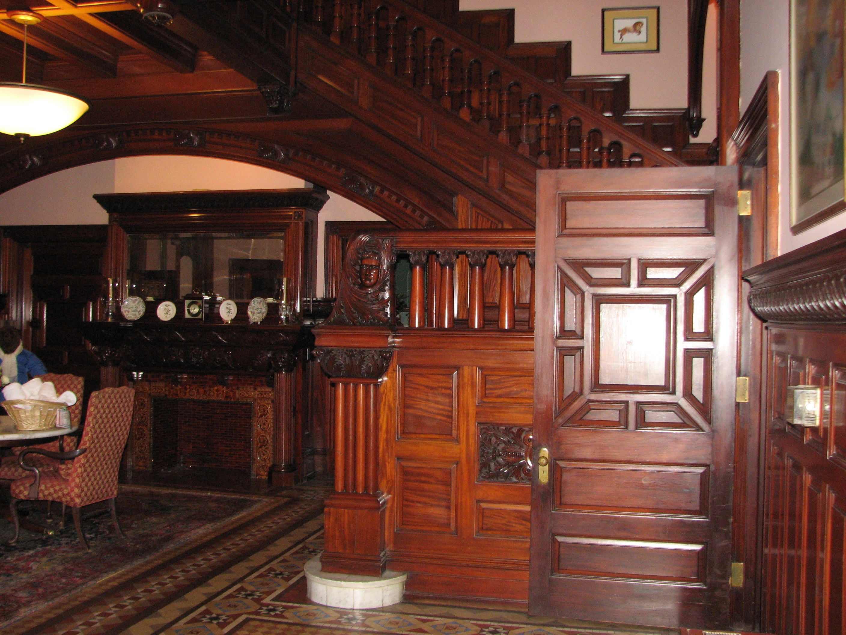 The elaborate interior of the house includes a grand oak staircase, tiled fireplaces, and parquet floors.