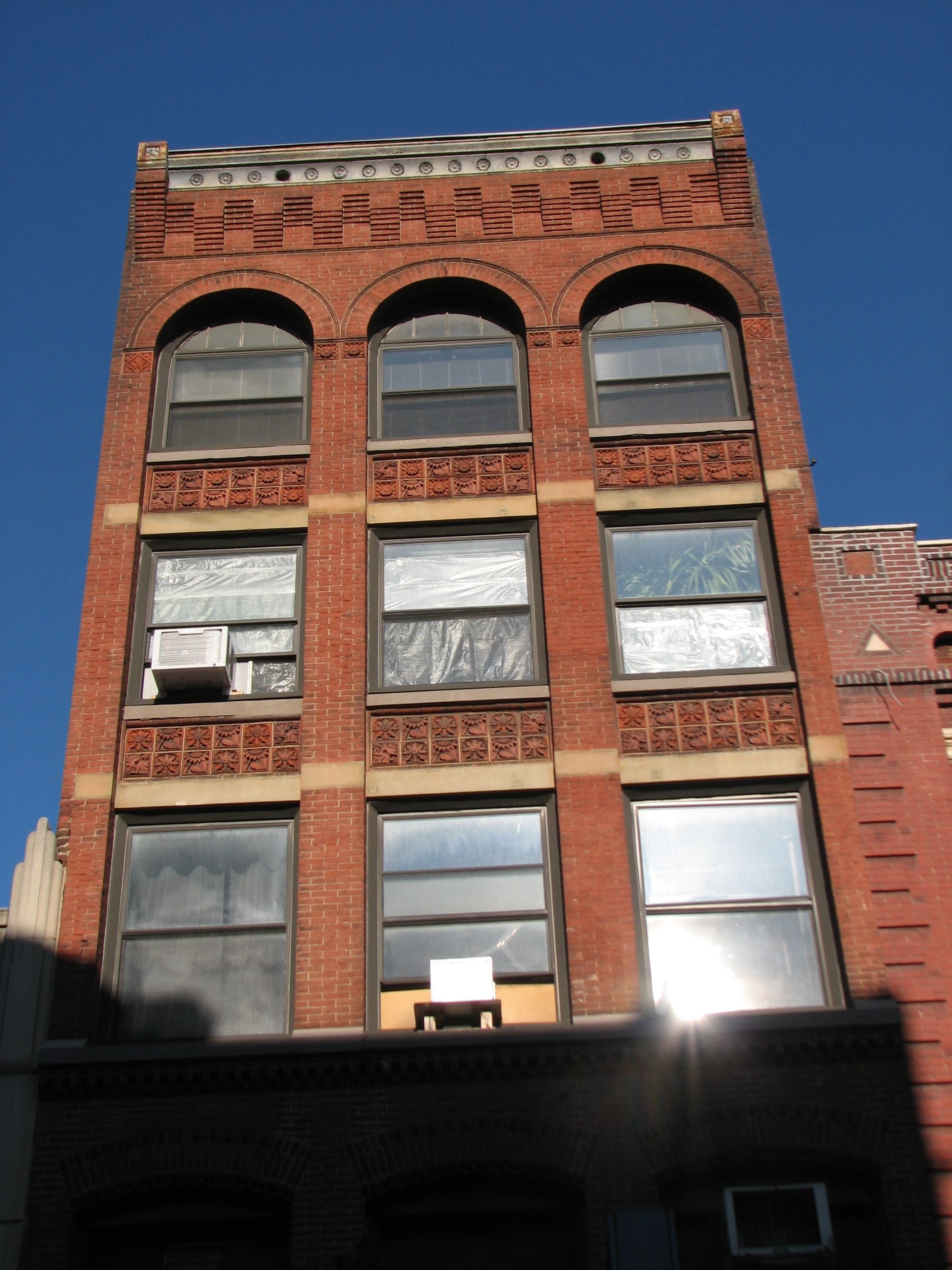 A commercial building on Sansom's north side features terra cotta tiles and corbelled brick.