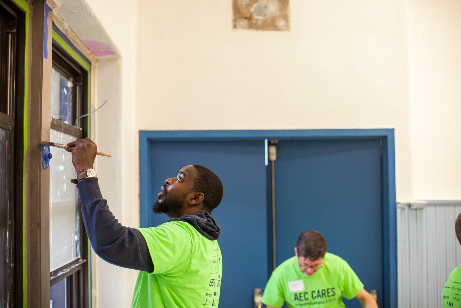 Andre Wright paints puts a new coat of paint on a window frame in the Sharswood Athletic Rec Center. (Brad Larrison for NewsWorks)
