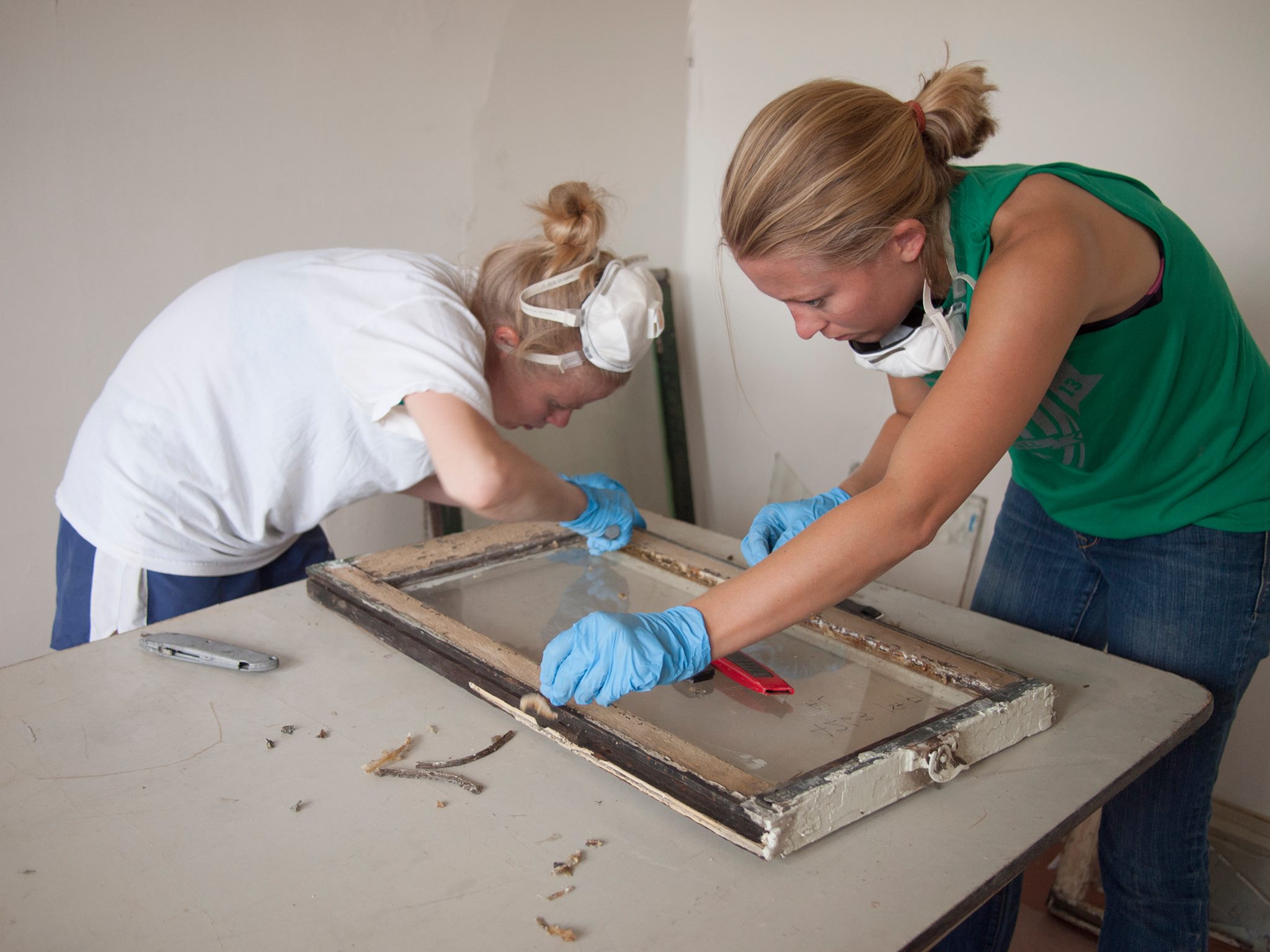 Claire Leftwitch (left) and Lindsey Allen restore windows on Viola Street in August 2014 | courtesy of Young Friends of the Preservation Alliance