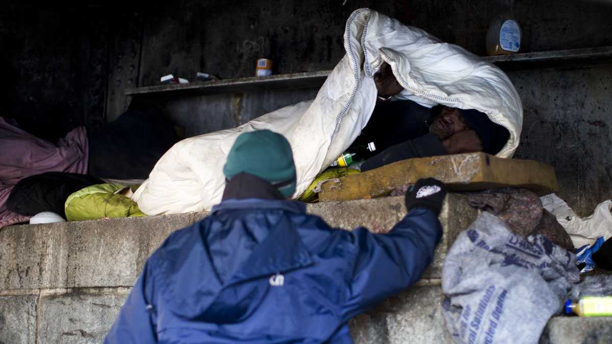 Project H.O.M.E. Outreach Response Worker Sam Santiago, center, assisting a homeless man sleeping under a bridge in Philadelphia. (AP Photo/Matt Rourke)