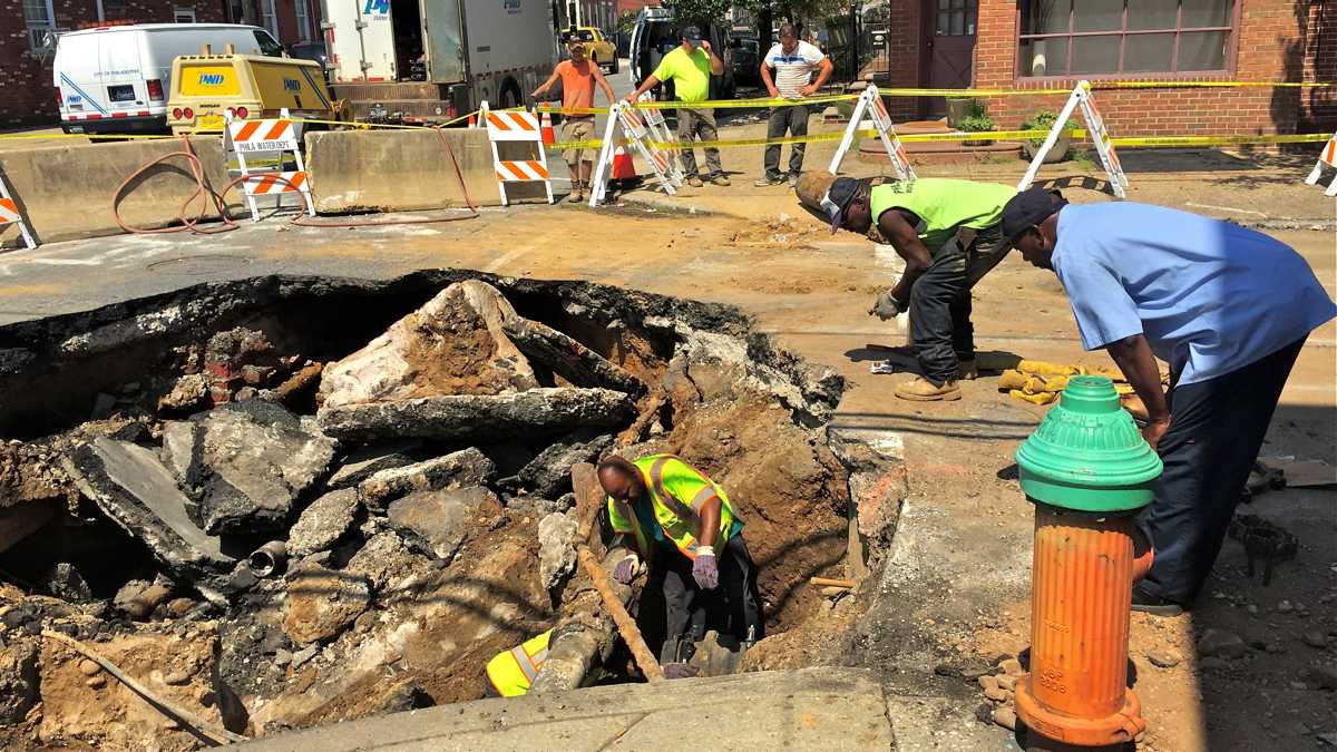 Workers examine a sinkhole in Kensington. (Bobby Allyn/WHYY)