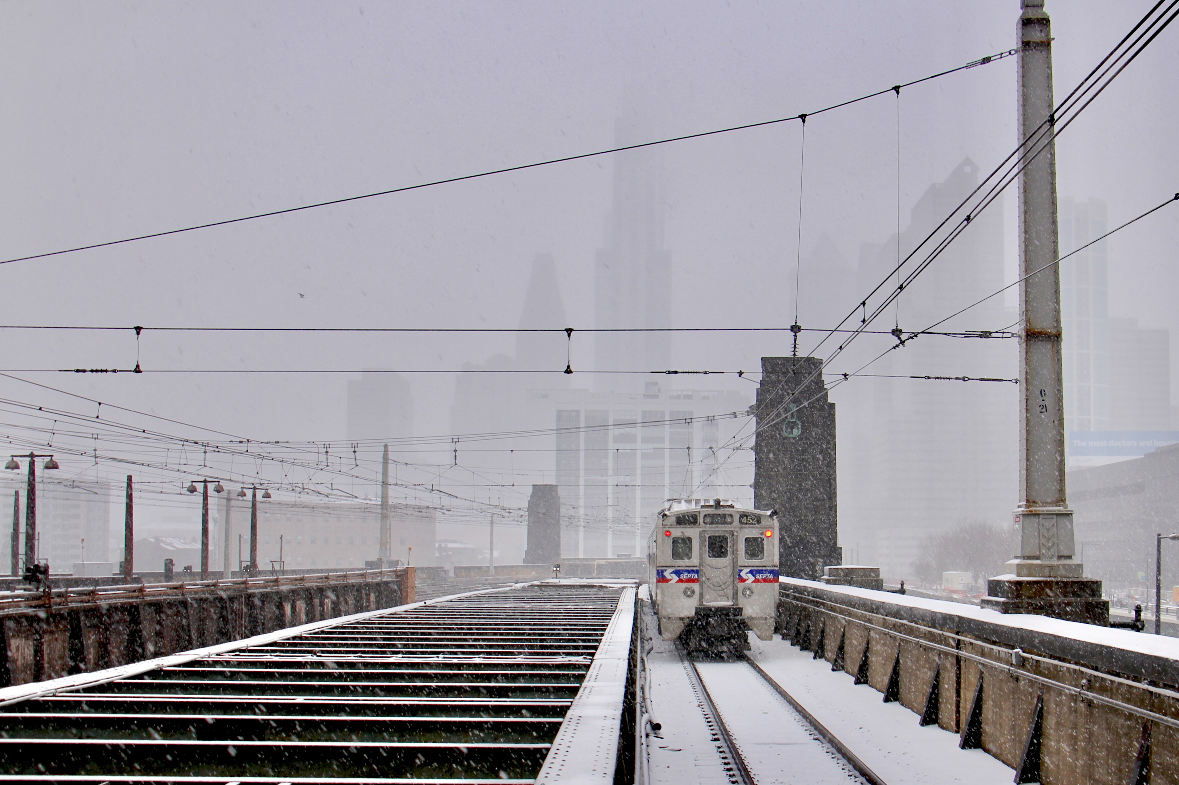 A regional rail train departs 30th Street Station as the snow intensifies. (Emma/Lee/WHYY)