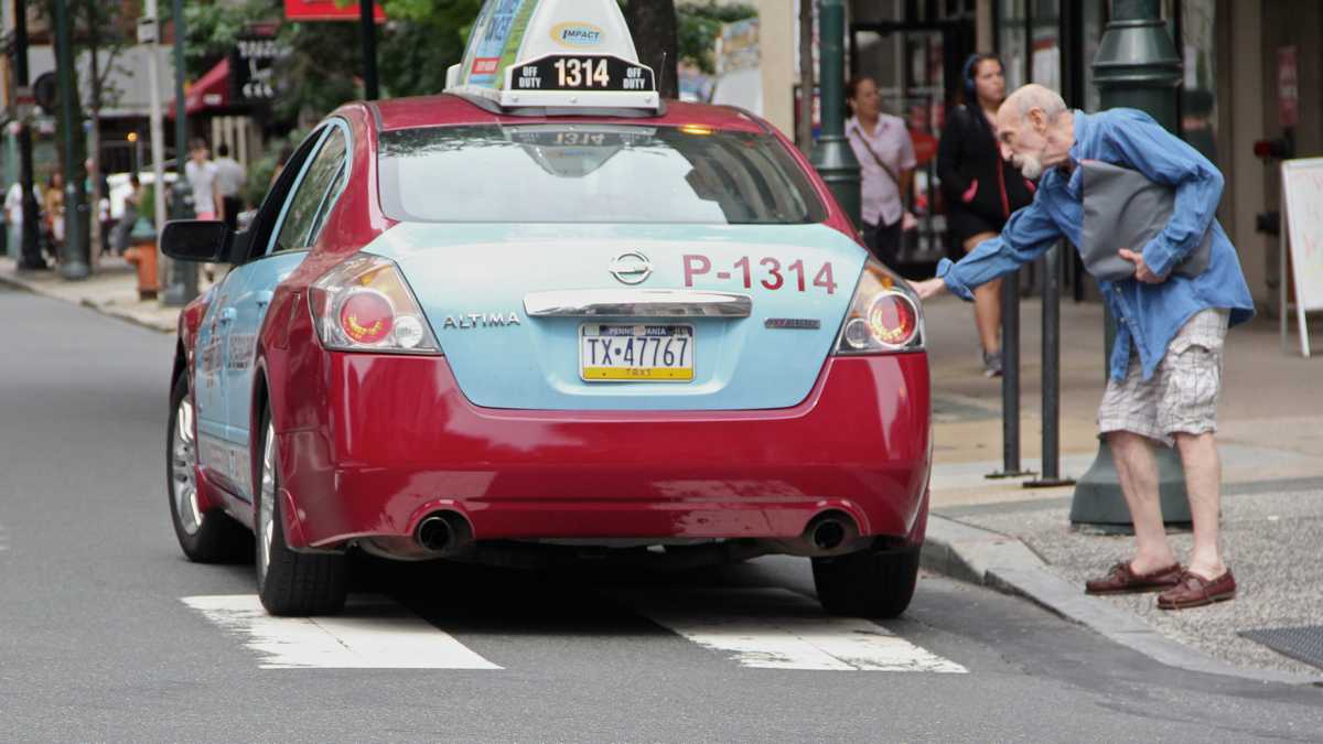 A taxi cab picks up a passenger in Philadelphia. (Emma Lee / WHYY)