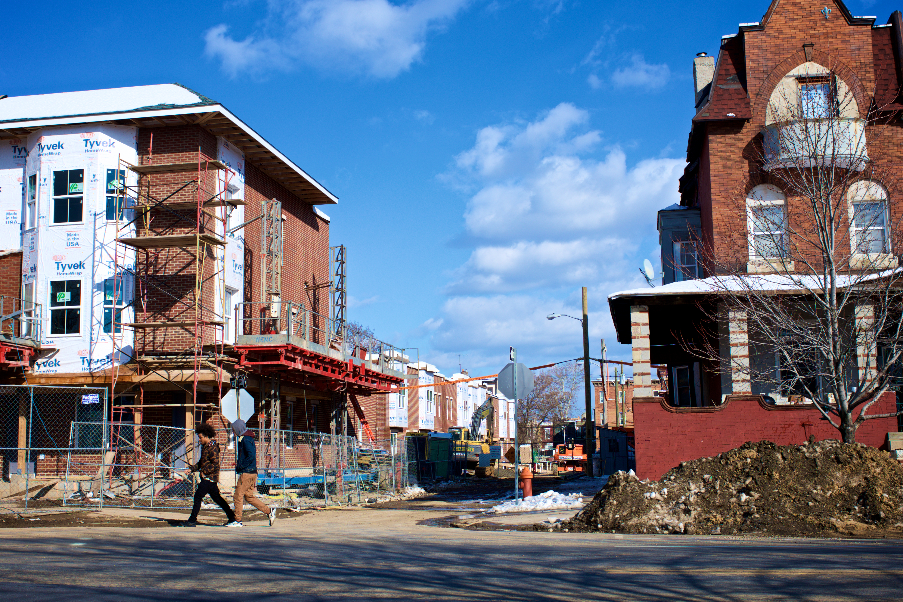 Two young men walk past a rehab project in Strawberry Mansion. (Bas Slabbers/WHYY)