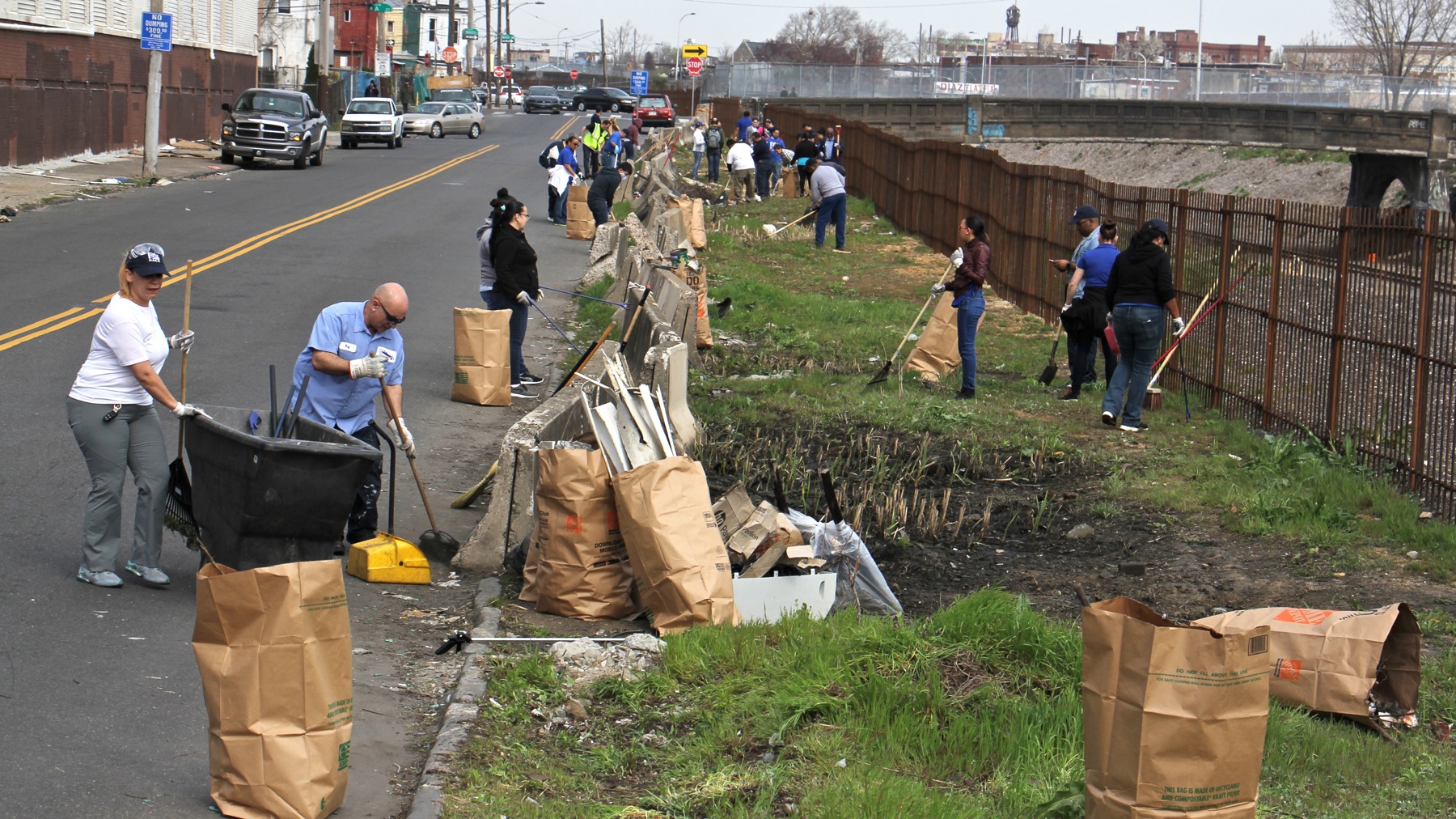 Workers and volunteers clean up trash in preparation for a new greenway alongside the former site of a notorious Kensington heroin encampment. (Emma Lee/WHYY)