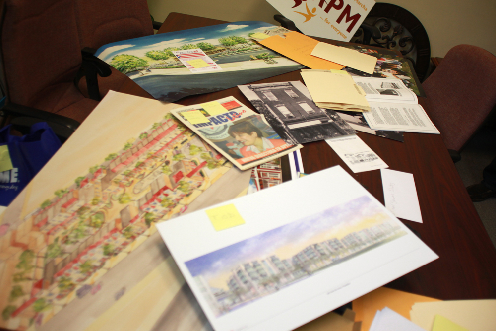 Random documents, photographs and sketches are laid across a conference table at the APM offices located on 4301 Rising Sun ave.