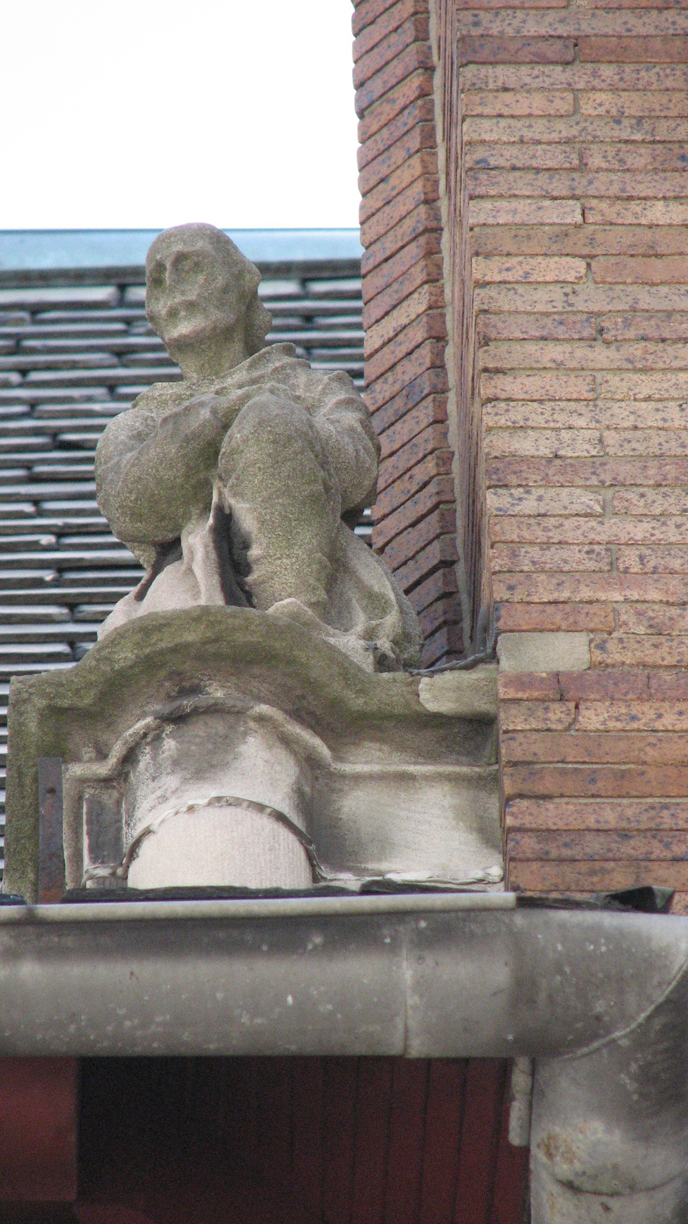 The figure of a man kneels on the slate roof.