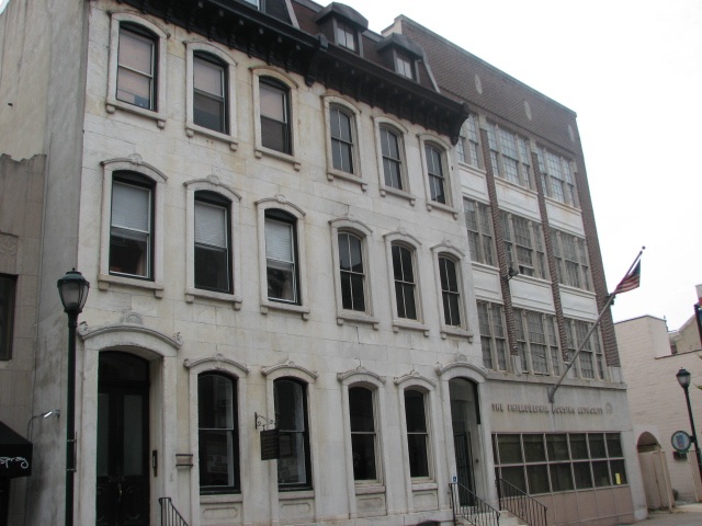 The neighboring building is a stately 19th-century residential structure.