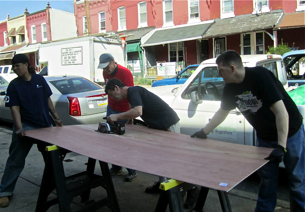 Volunteers brace plywood as it is cut for use in one of the Aspen Street homes. | Christine Fisher