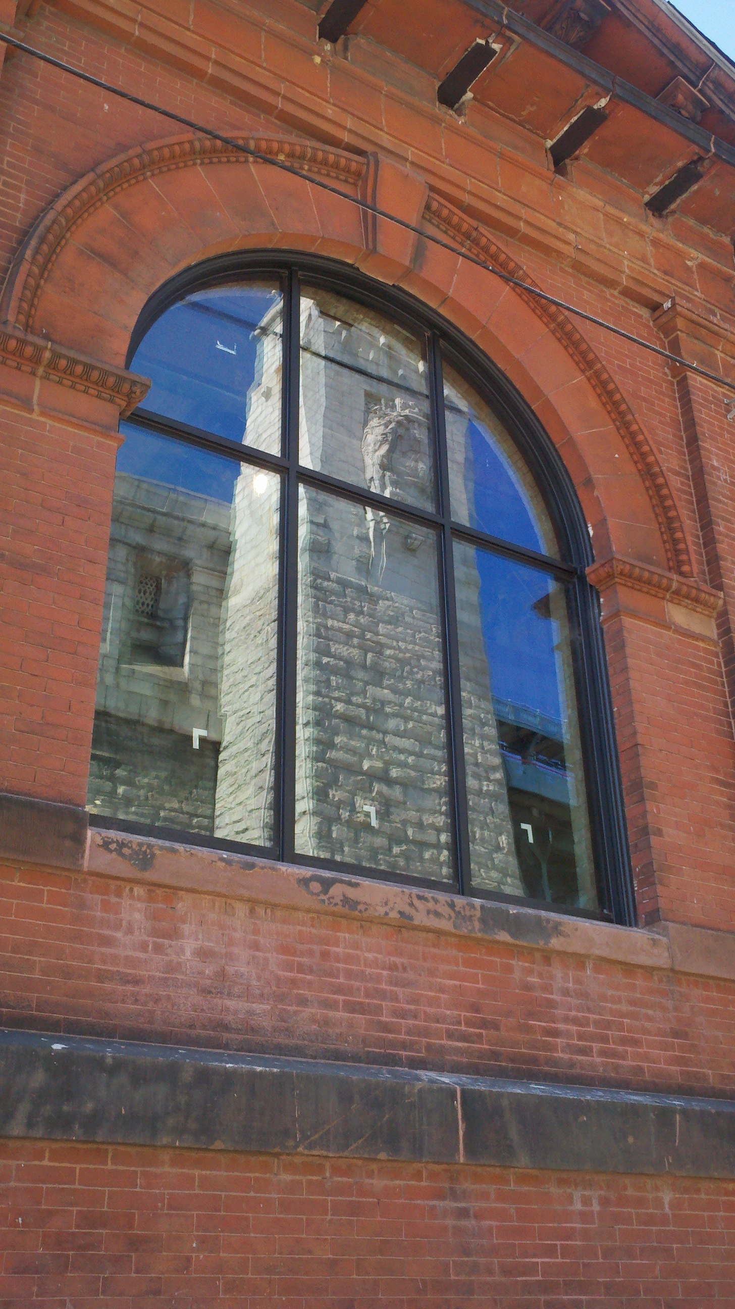 A tower of the Ben Franklin Bridge is reflected in a new FringeArts window