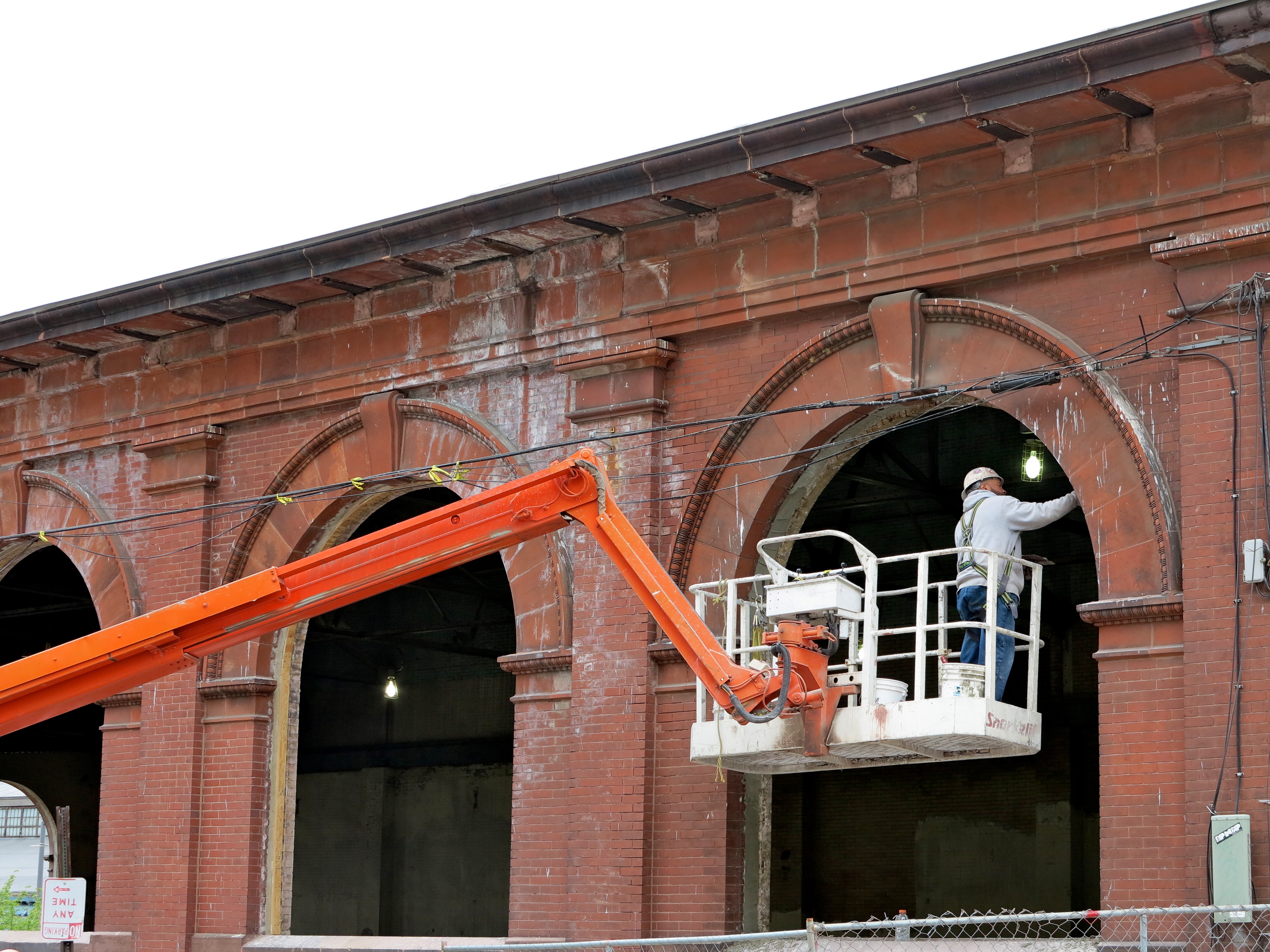 A worker patching an arched masonry window opening along Race Street.
