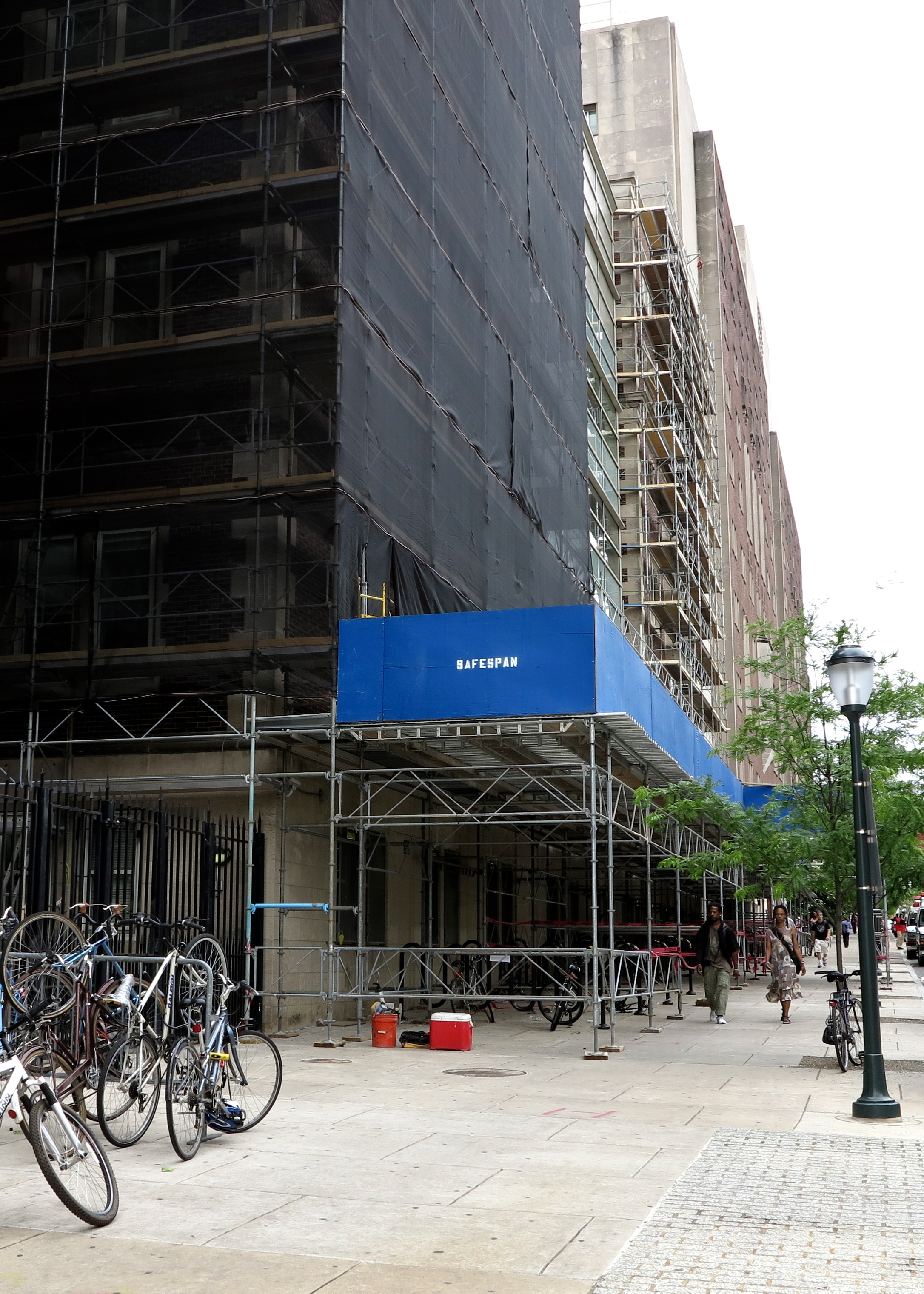 An example of scaffolding wrapped in safety netting and a sidewalk shed outside of the Hospital of the University of Pennsylvania.