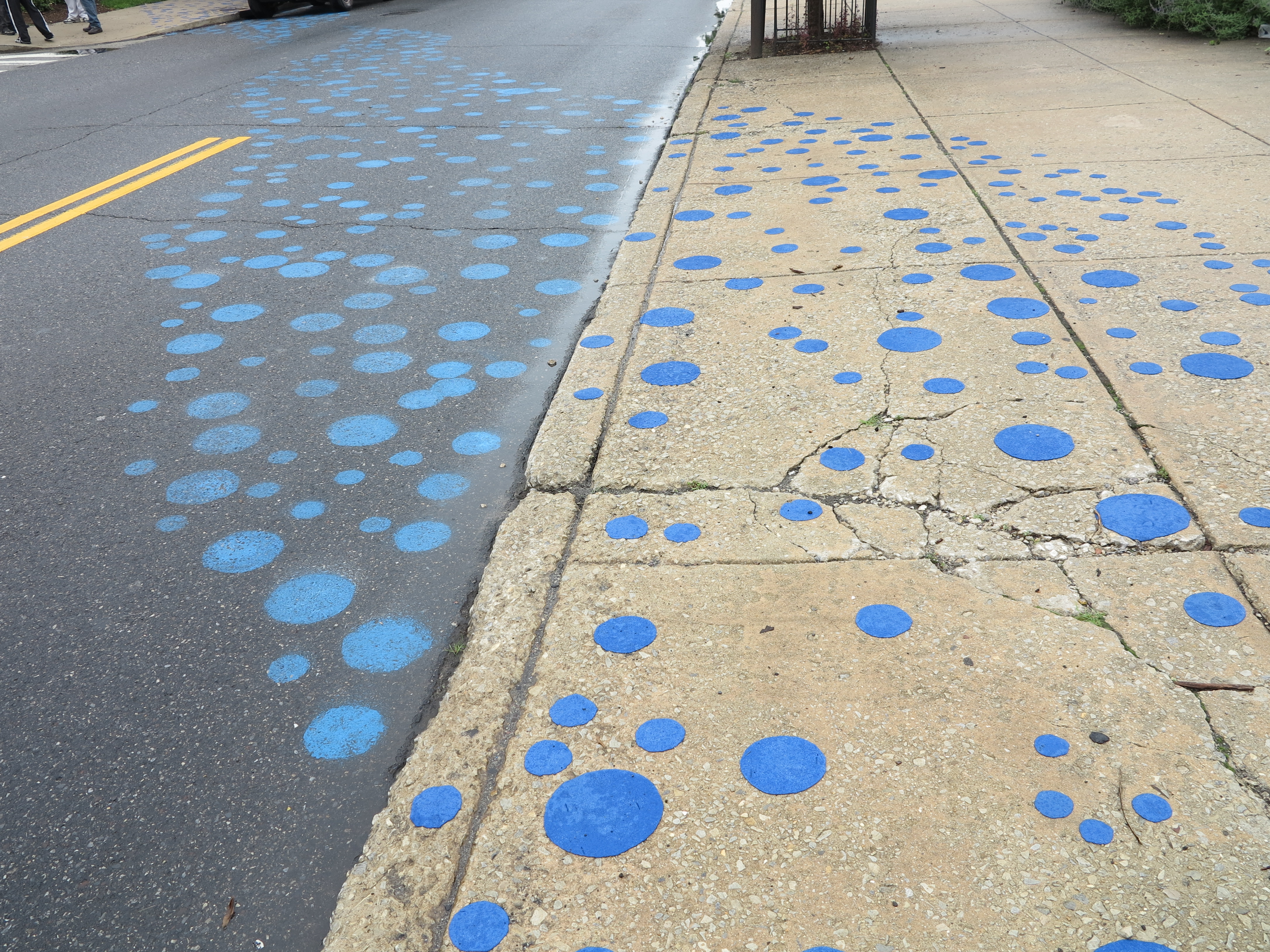 Dots were painted on the street using surveyor's paint and dots on the sidewalk were adhered using a torch.