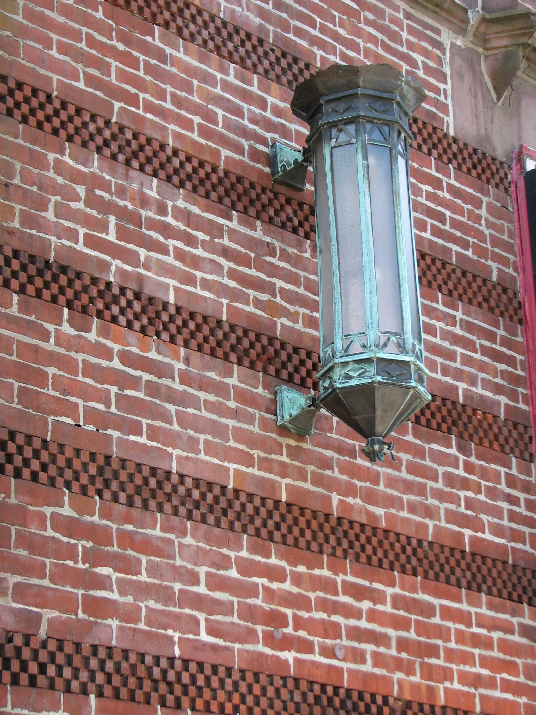 Original lamp fixtures still hang on the decorative brick on either side of the building’s entrance.