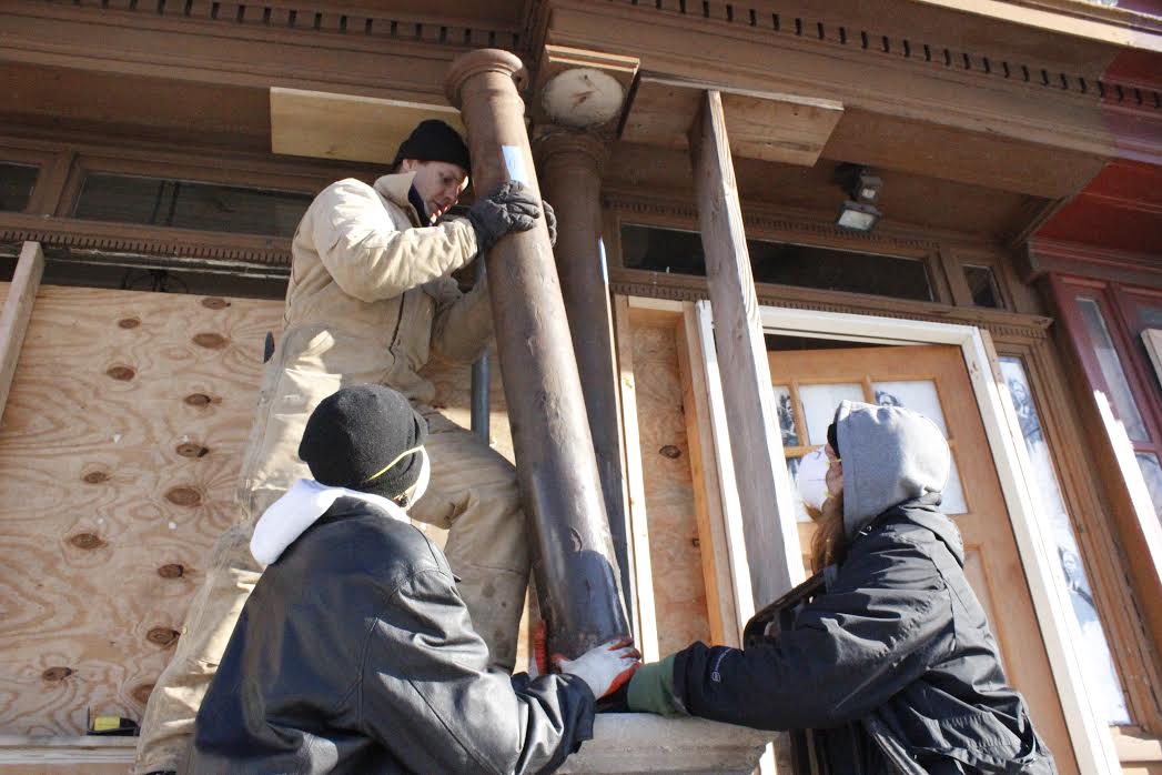 Two of the YouthBuild students help Andrew Palewski position one of the original porch columns | YouthBuild Philadelphia Charter