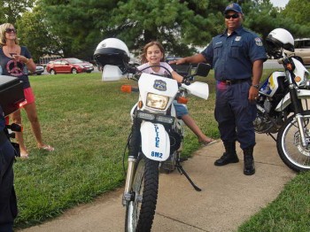 Denise and Marissa Gibson along with an 8th District officer try out a motorcycle at the National Night Out event.