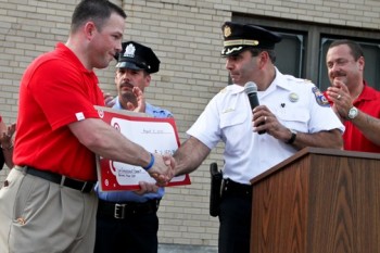 Captain Joseph Joseph F. Zaffino, Commanding Officer of the 7th District Police Department shakes hands with a representative of Target and accepts a check  on behalf of the Captain of the 2nd Distric