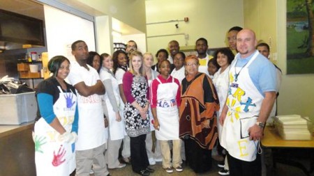 Excel Academy South Executive Director Kevin Marx, Culinary Arts Teacher Lari Luckenbill and St. John’s Hospice Social Services Supervisor Iraina Salaam join the school’s culinary arts students, who p